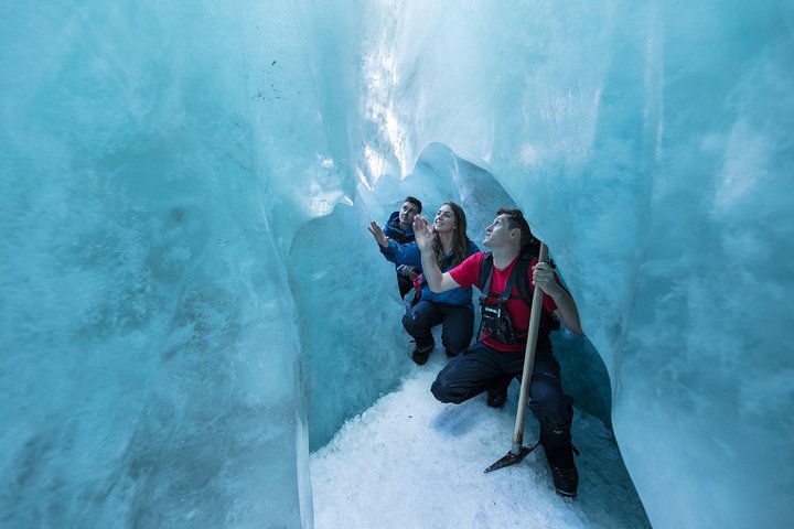 Franz Josef Glacier heli-hike in New Zealand, group exploring blue ice cave interior