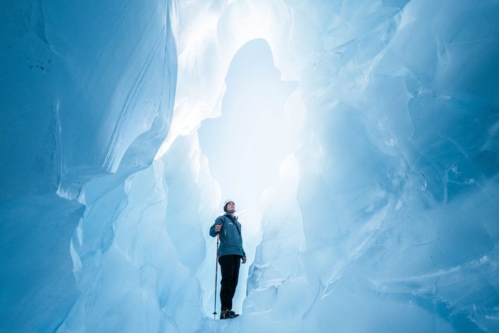 Inside a blue ice cave in Iceland, natural light filtering through glacial ice walls