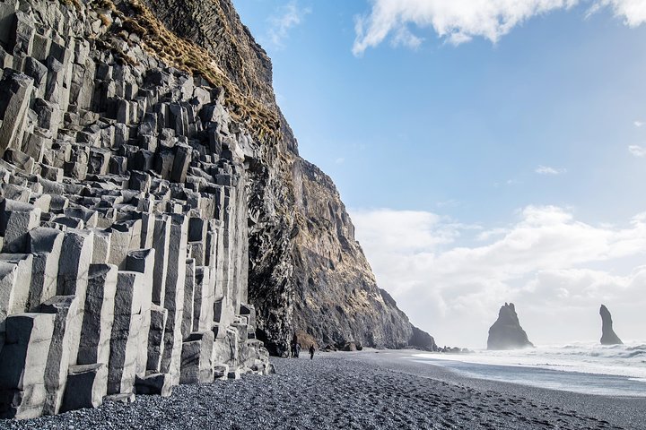 Small group hiking roped together across a glacier with crampons on the South Coast of Iceland